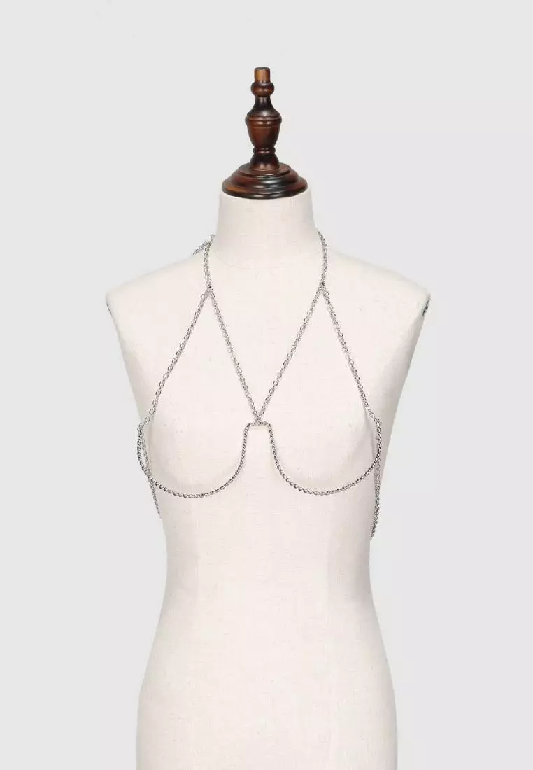 Beige bra on white mannequin with metal rings. Nipple piercing